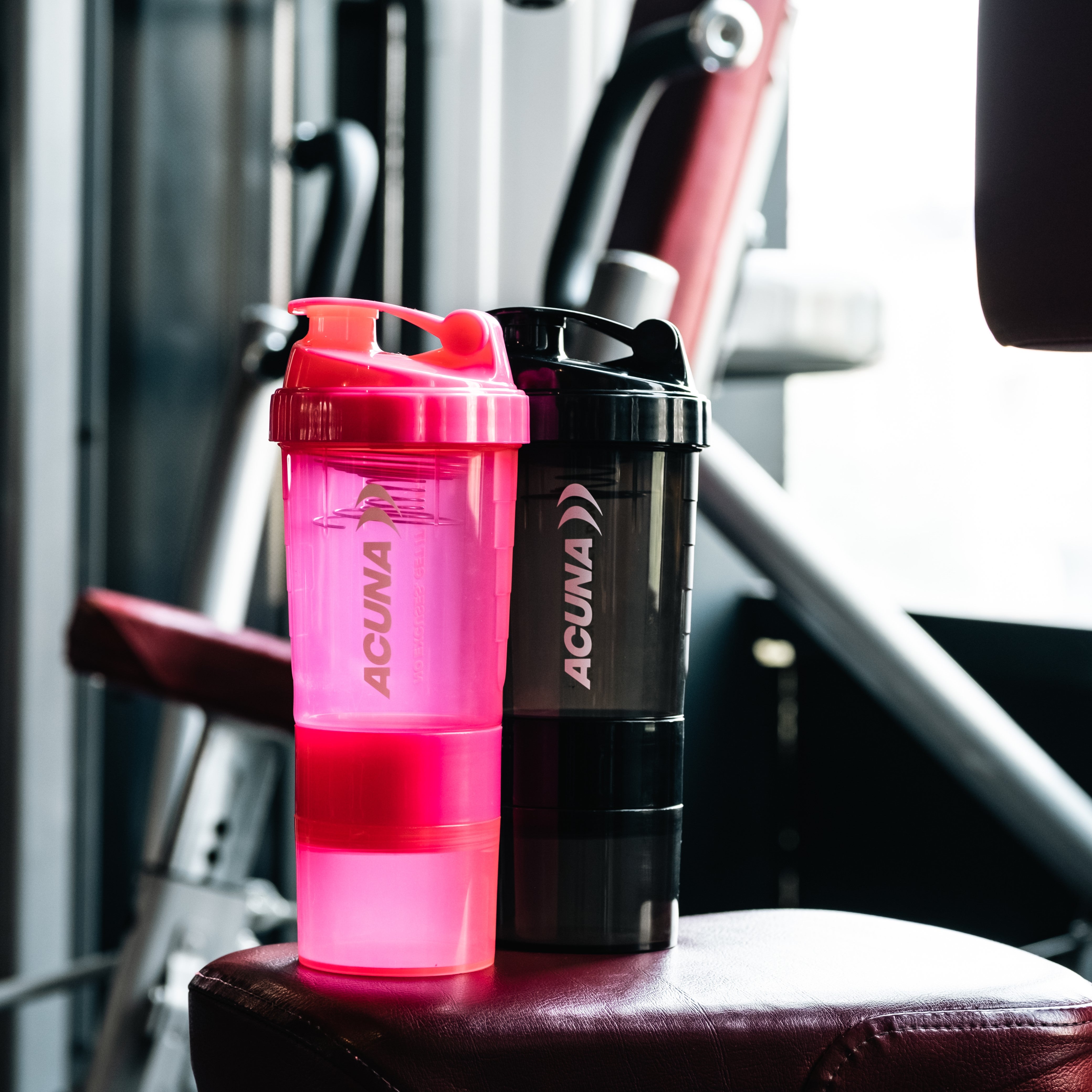 Two shaker bottles positioned on a gym bench, ready for use.